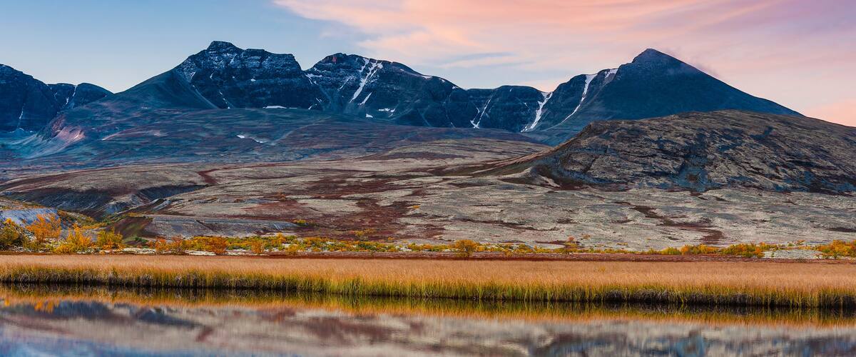 A mountain range with a clear reflection in a calm body of water.