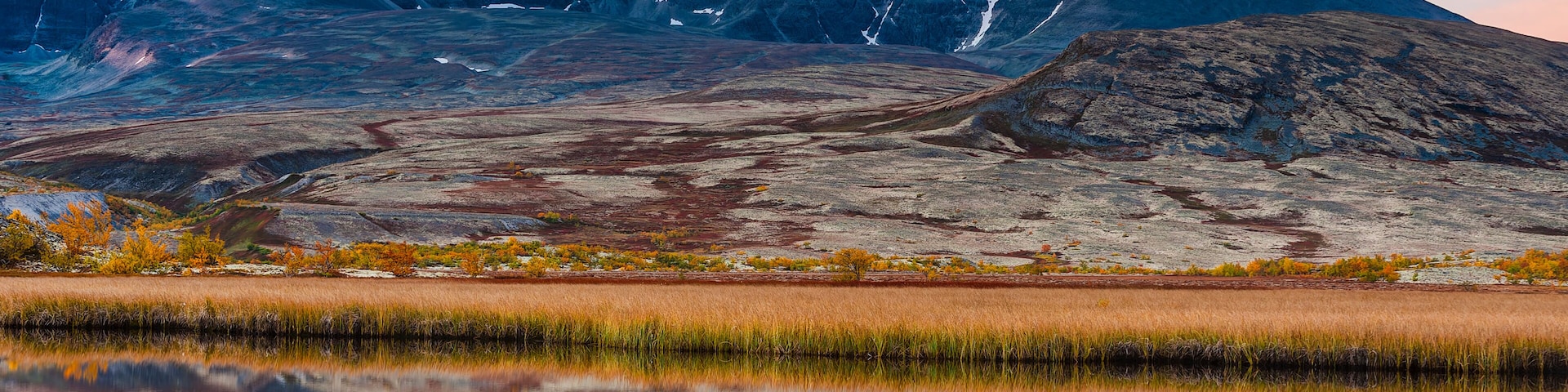 A mountain range with a clear reflection in a calm body of water.