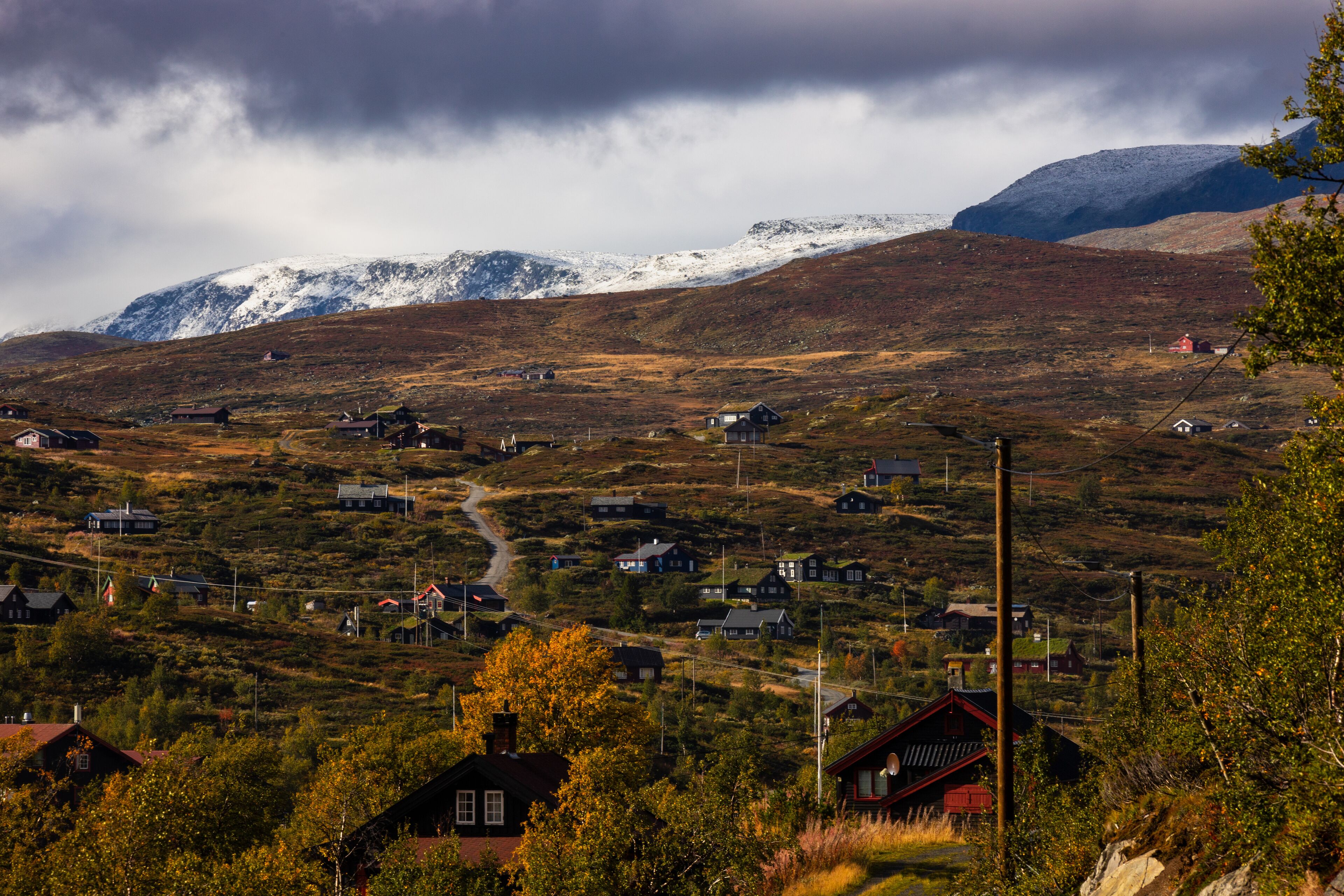 A typical landscape of the Hardangervidda in Norway. All pictures were taken in autumn. On the picture you see a small village in front of  snowcoverd mountains.