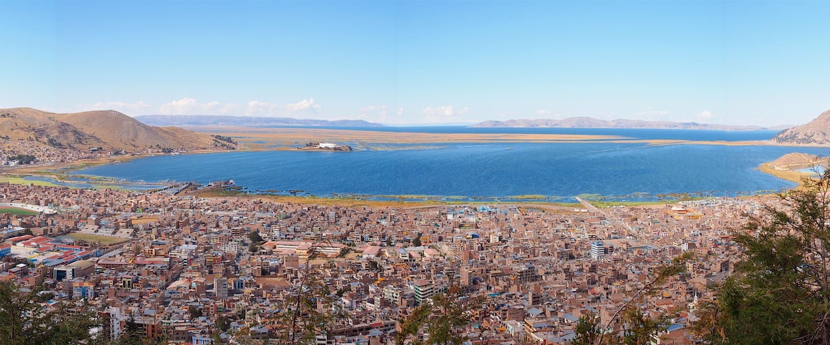 A coastal city with a large body of water, mountains in the background, and dense urban development.