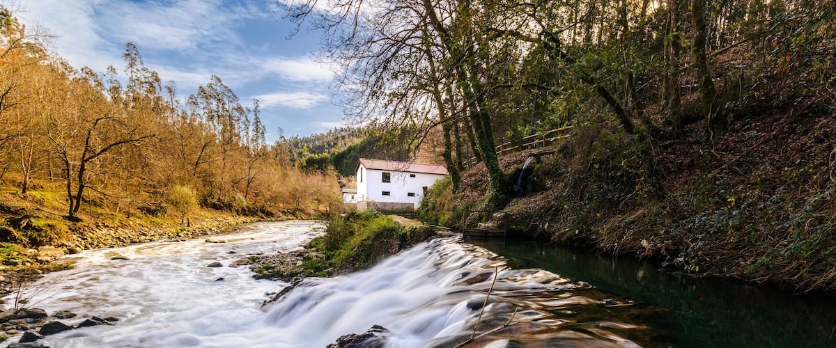 A flowing river with a house on a hill.