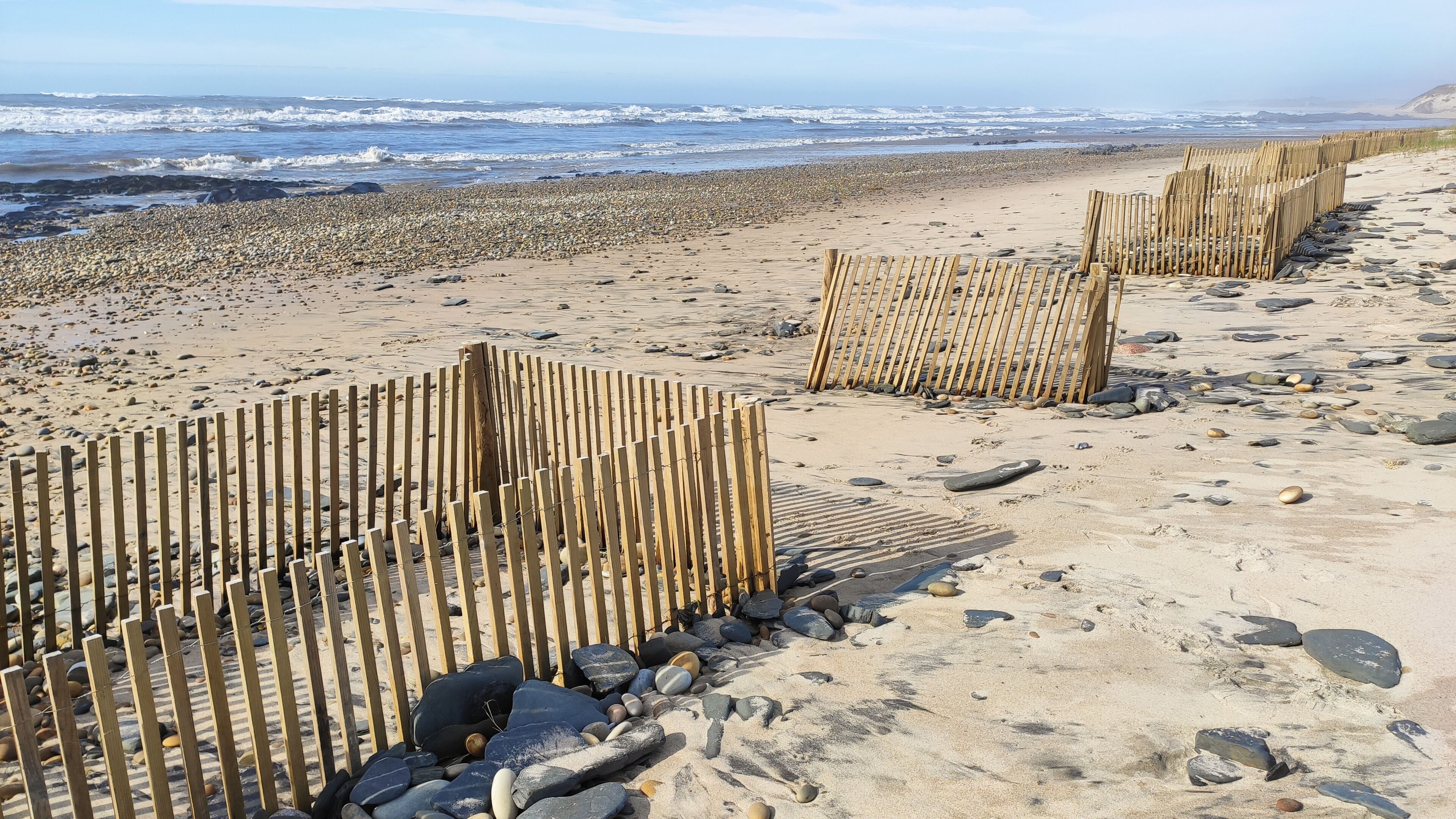 A sandy beach with wooden fences and scattered rocks.