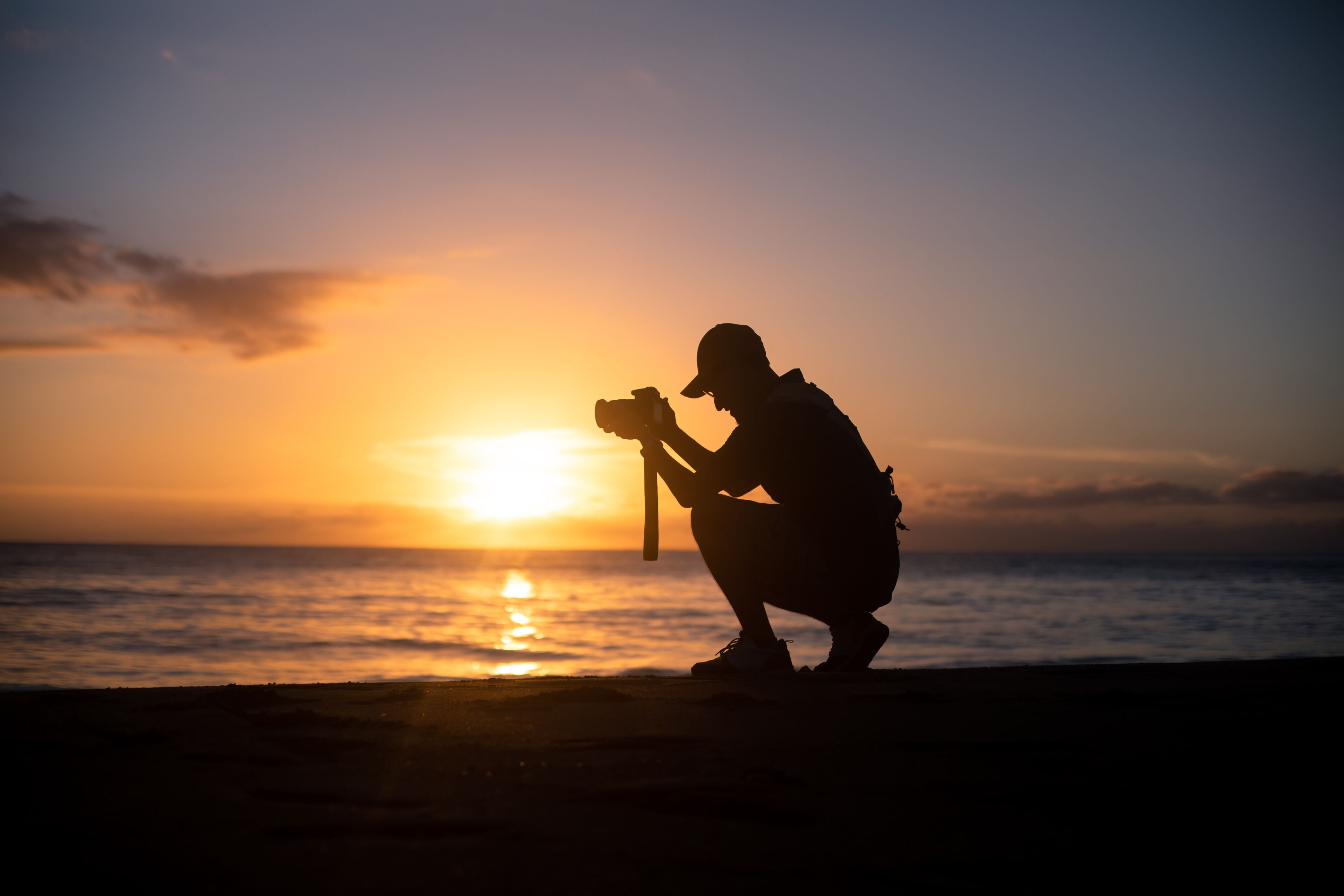 The silhouette of a male hobbyist photographer taking photos of a beautiful colorful sunset on the West Puerto Rico coast near Rincon
