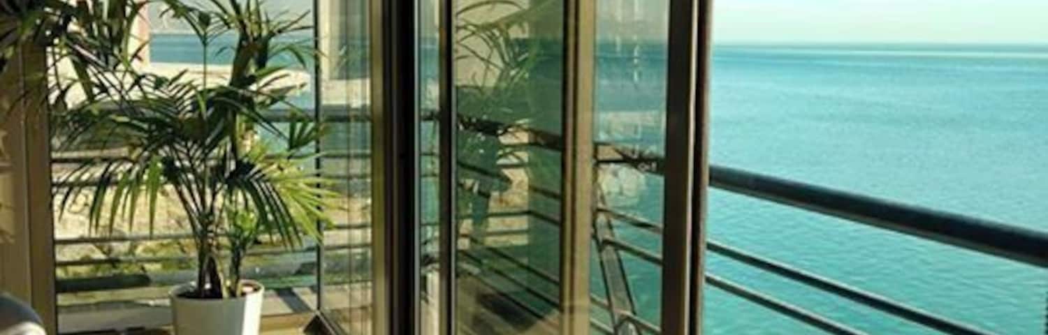 Ein Balkon mit Blick auf das Meer und ein Gebäude im Hintergrund.