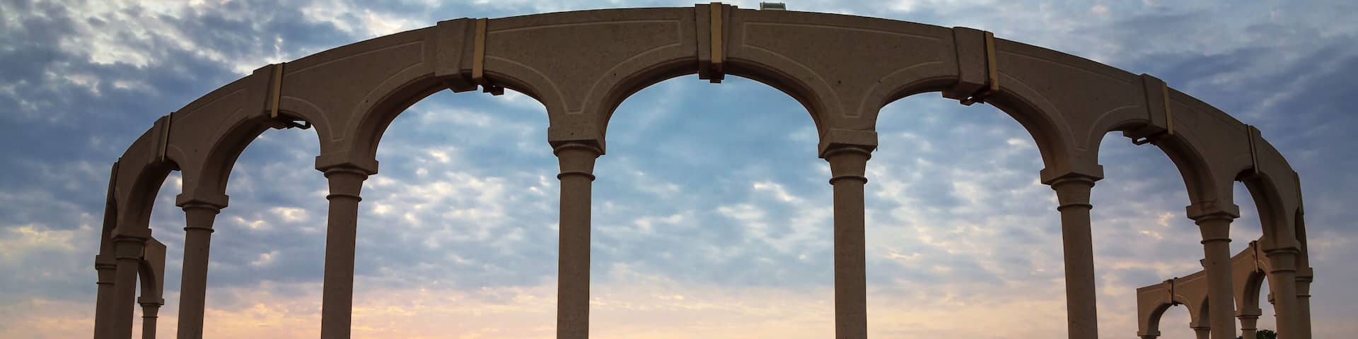 A seaside architectural structure with multiple arches and a red-tiled floor.