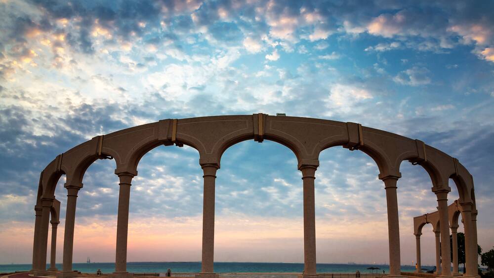 Une série d’arcades surplombant une promenade en bord de mer, avec un ciel au coucher du soleil.