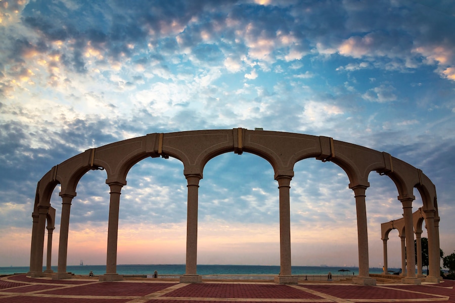 Una serie de arcos sobre un paseo marítimo con un cielo al atardecer.