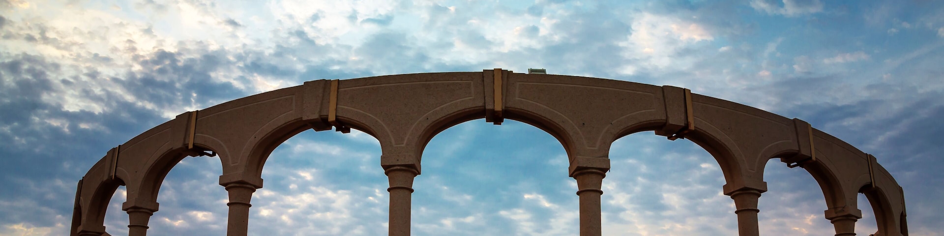 Una serie de arcos sobre un paseo marítimo con un cielo al atardecer.