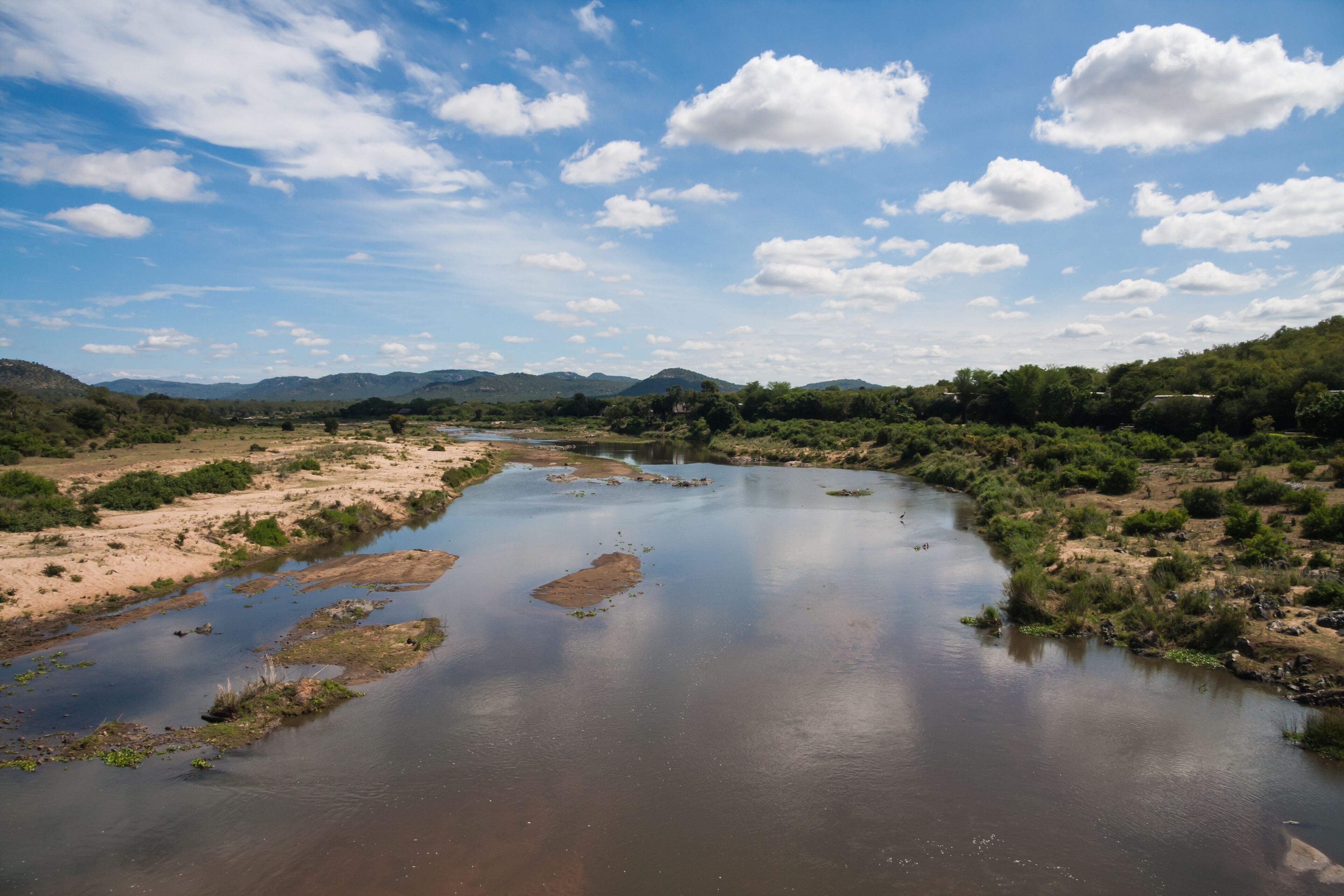 A river winding through a valley with mountains in the background and a clear sky.