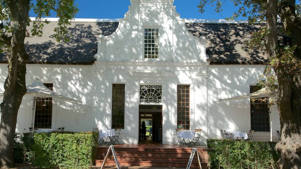 Un bâtiment de style colonial, de couleur blanche, avec une entrée centrale, flanqué de deux grandes fenêtres et surmonté d’un tympan décoratif.