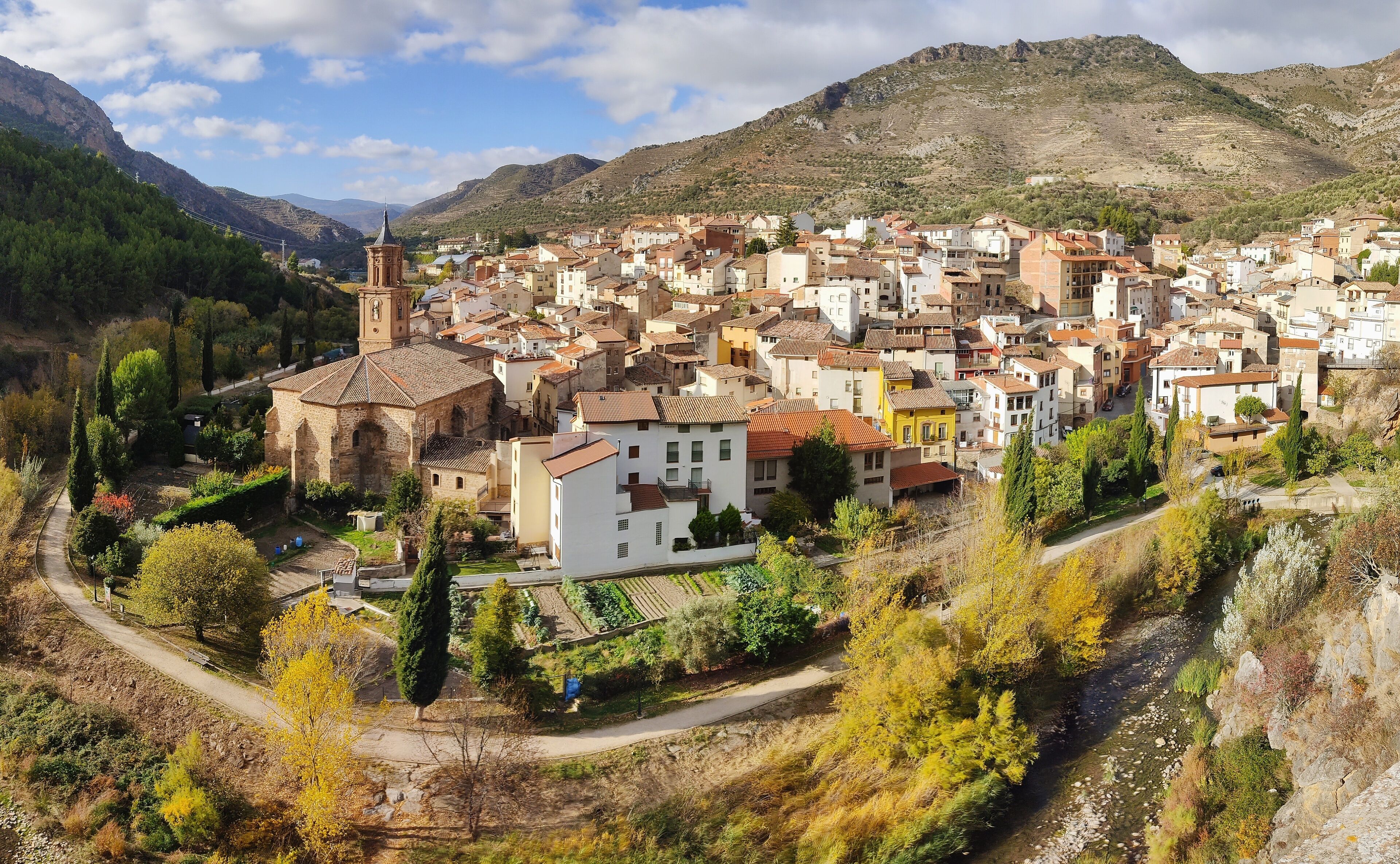 A town nestled in a valley with a prominent church and a river running through it.