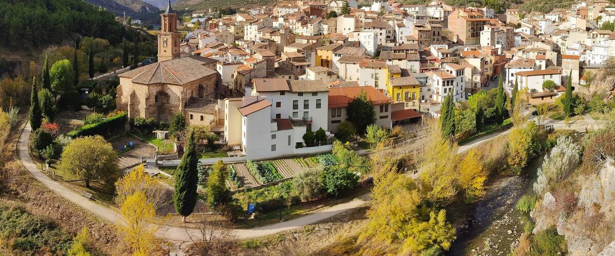 A town nestled in a valley with a prominent church and a river running through it.