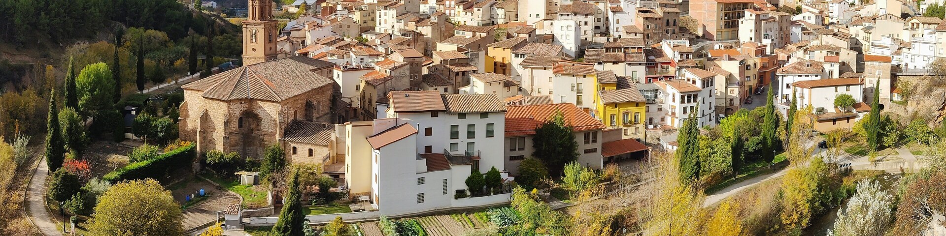 A town nestled in a valley with a prominent church and a river running through it.