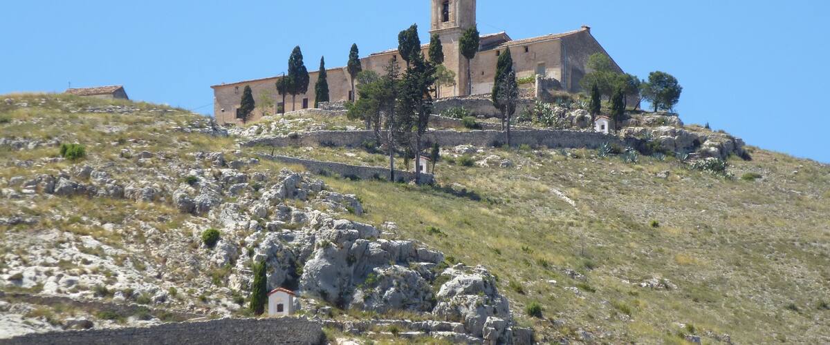 A church on a hill with stone walls and trees.
