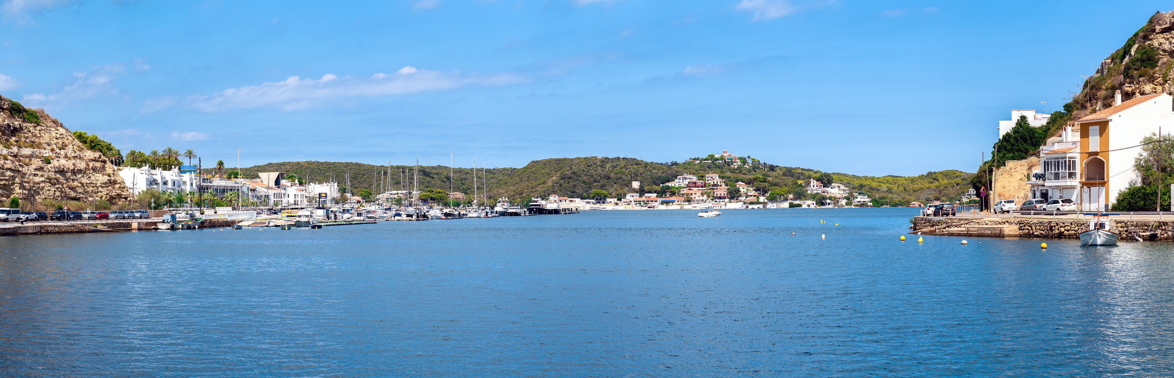 A coastal town with a marina, boats, and buildings along the waterfront.