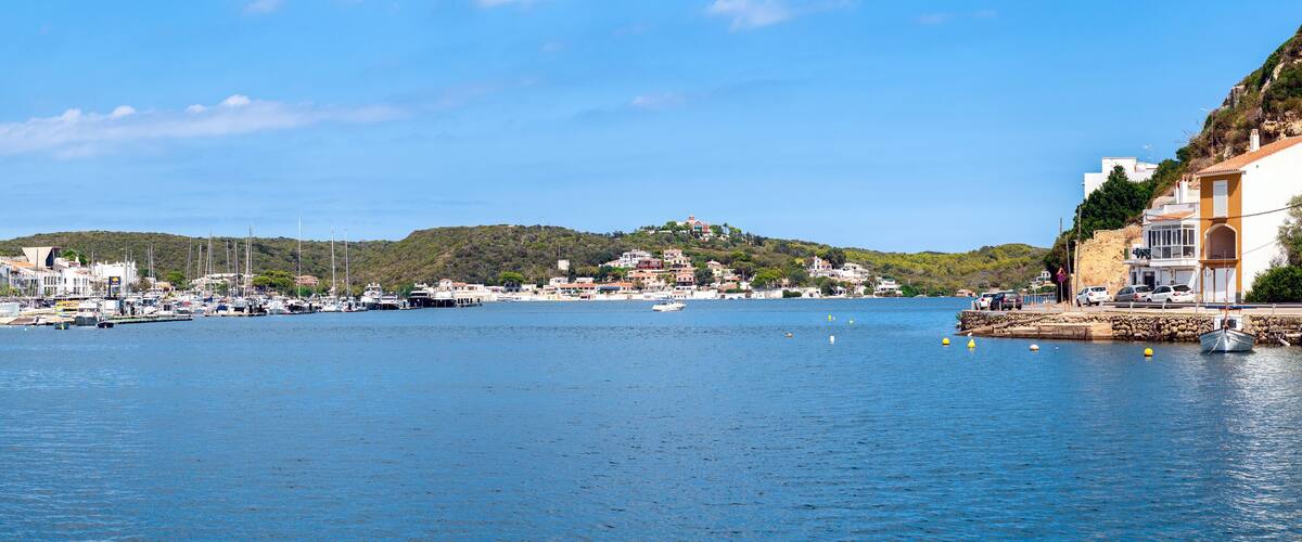 A coastal town with a marina, boats, and buildings along the waterfront.