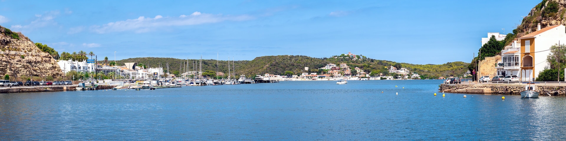 A coastal town with a marina, boats, and buildings along the waterfront.