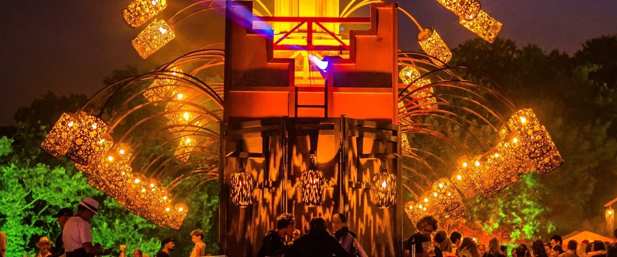 A brightly lit tower with a spiral staircase and a crowd of people around it.
