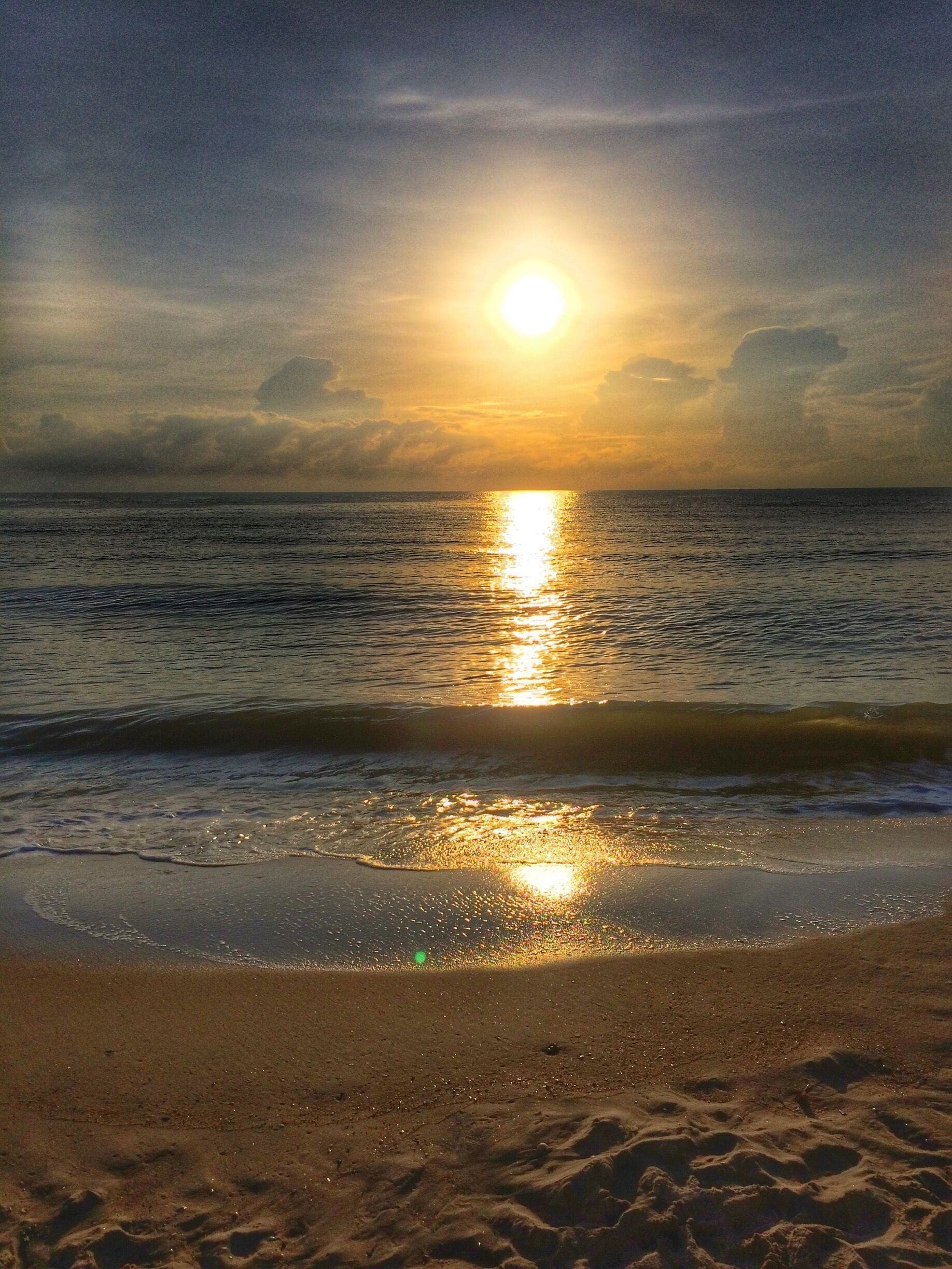 Una playa con el sol reflejándose en el agua.