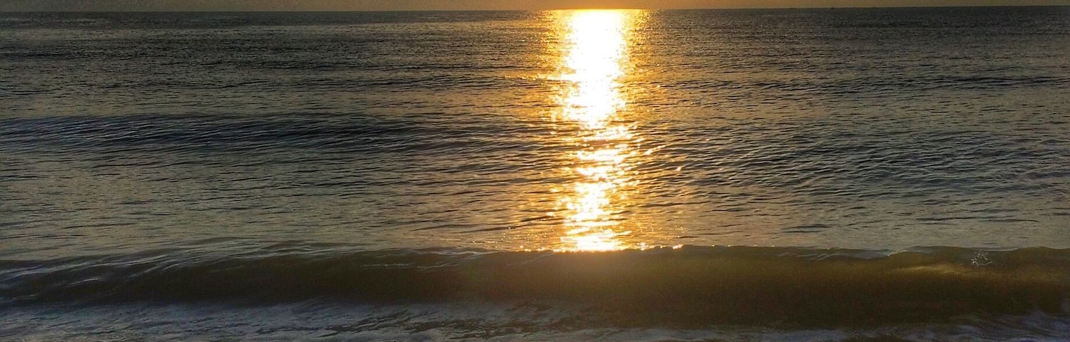 Una playa con el sol reflejándose en el agua.