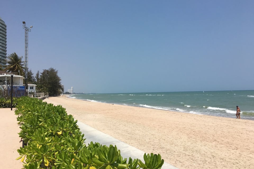 A beach with a clear sky, ocean waves, and a person walking.