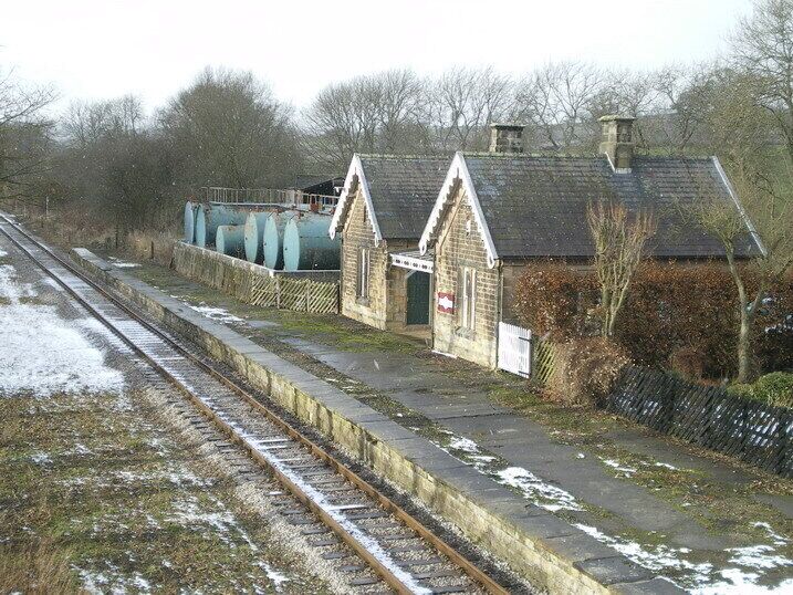 A railway station with a small brick building, a platform, and a railway track.