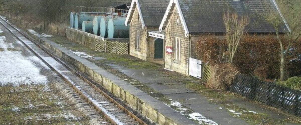 A railway station with a small brick building, a platform, and a railway track.