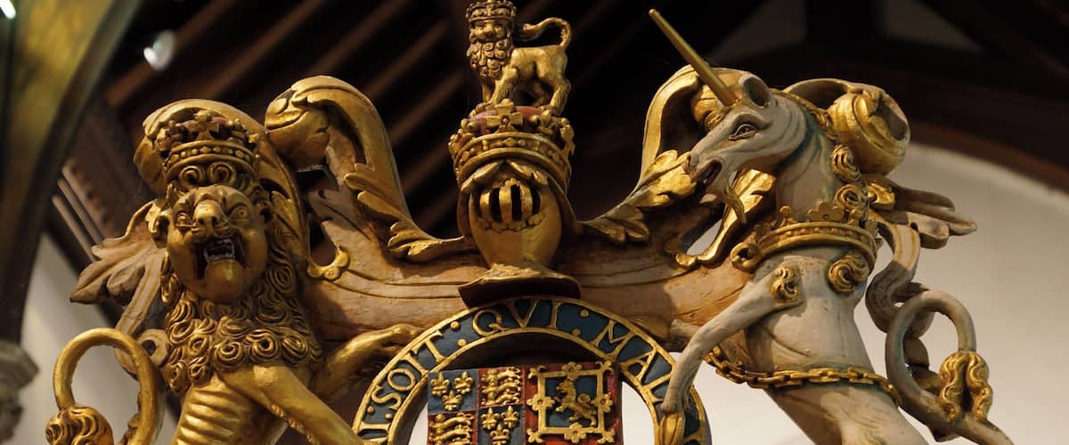 A golden coat of arms with a lion, unicorn, and crown.