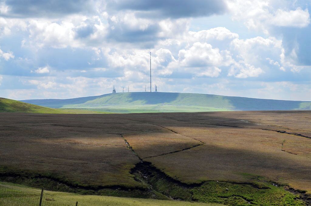 A vast, flat landscape with a gentle hill in the distance, under a partly cloudy sky.