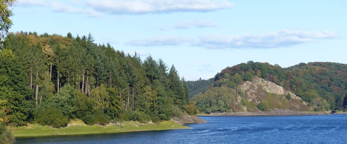 A calm lake surrounded by dense forests and hills.
