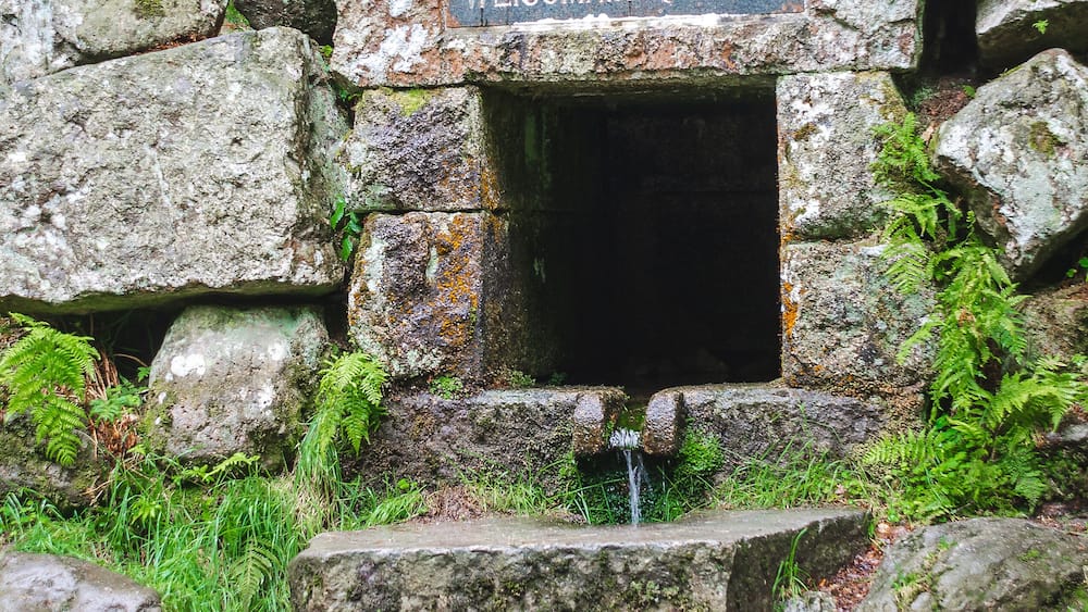 A stone structure with a sign reading "WEISSMANSOUELLE" and a small water spout.