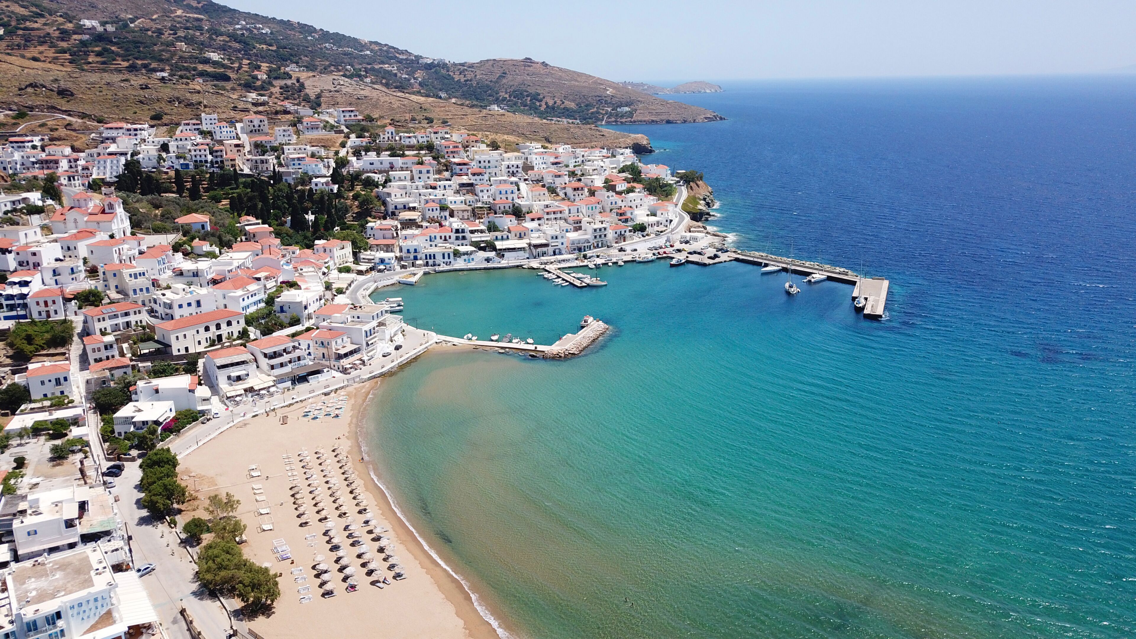 A coastal town with white buildings, a beach, and a pier extending into the sea.