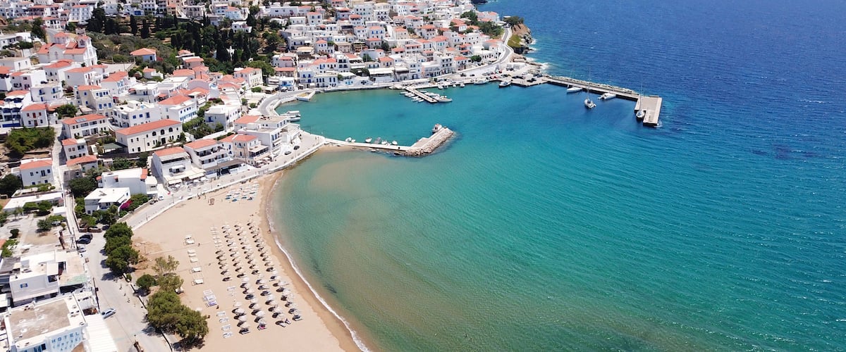A coastal town with white buildings, a beach, and a pier extending into the sea.