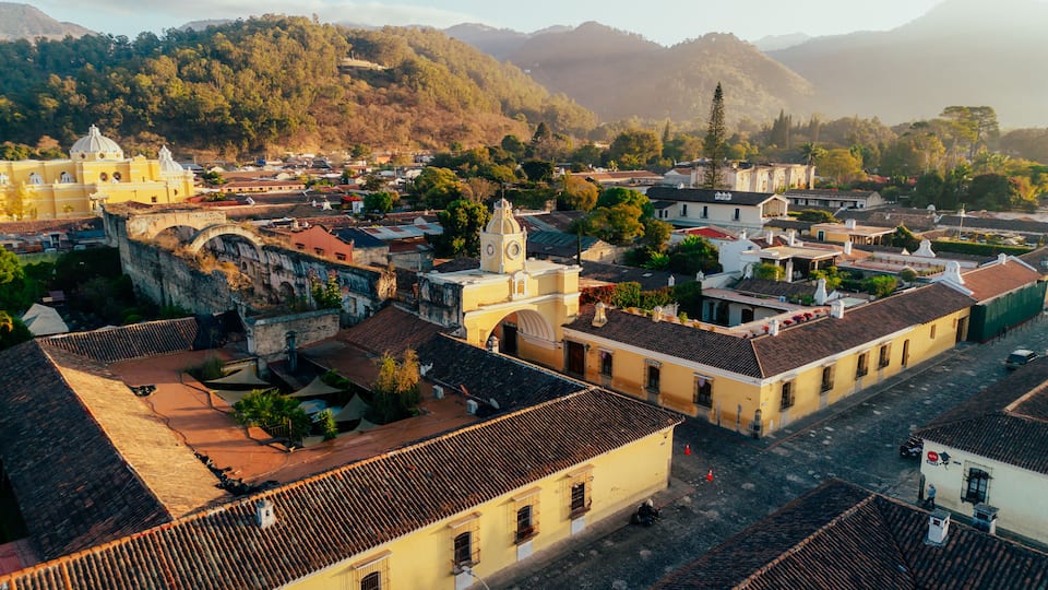 A historic town with colonial architecture, a prominent church, and surrounding mountains.