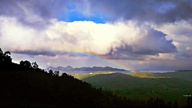 Une chaîne de montagnes avec un arc-en-ciel et des nuages.