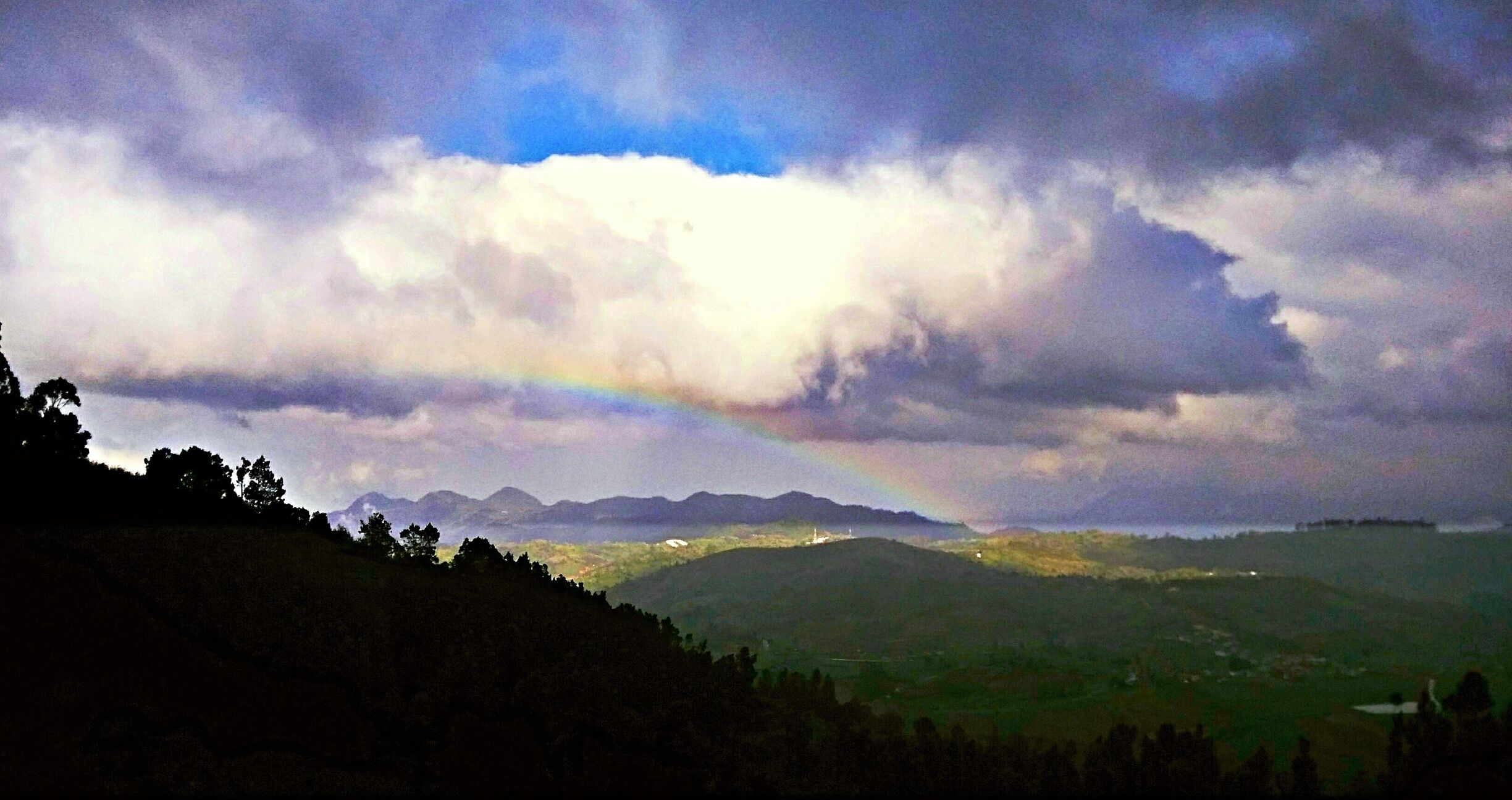 A mountain range with a rainbow and clouds.