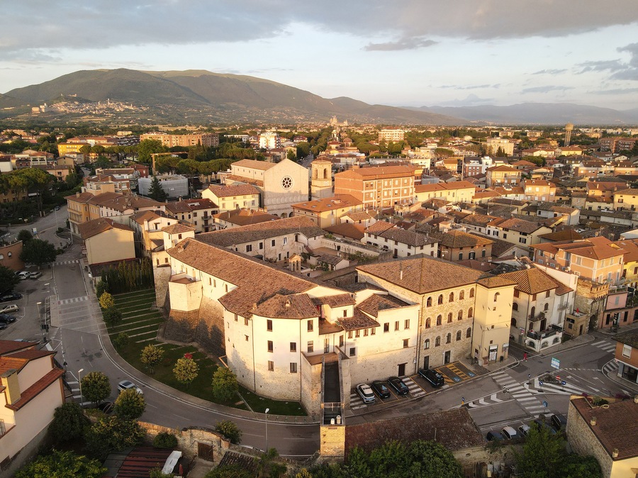 Un pueblo histórico con una iglesia destacada, una torre circular y un telón de fondo montañoso.