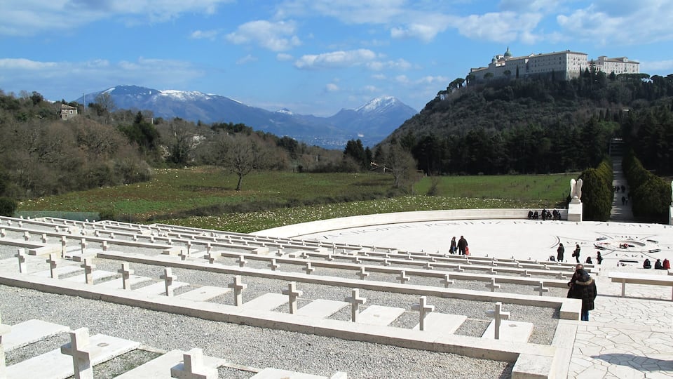 A cemetery with white crosses, a large open area, and a castle on a hill in the background.