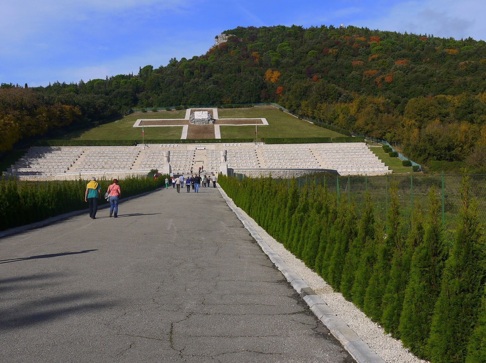 A large open-air amphitheater with tiered seating, surrounded by a forested hillside.