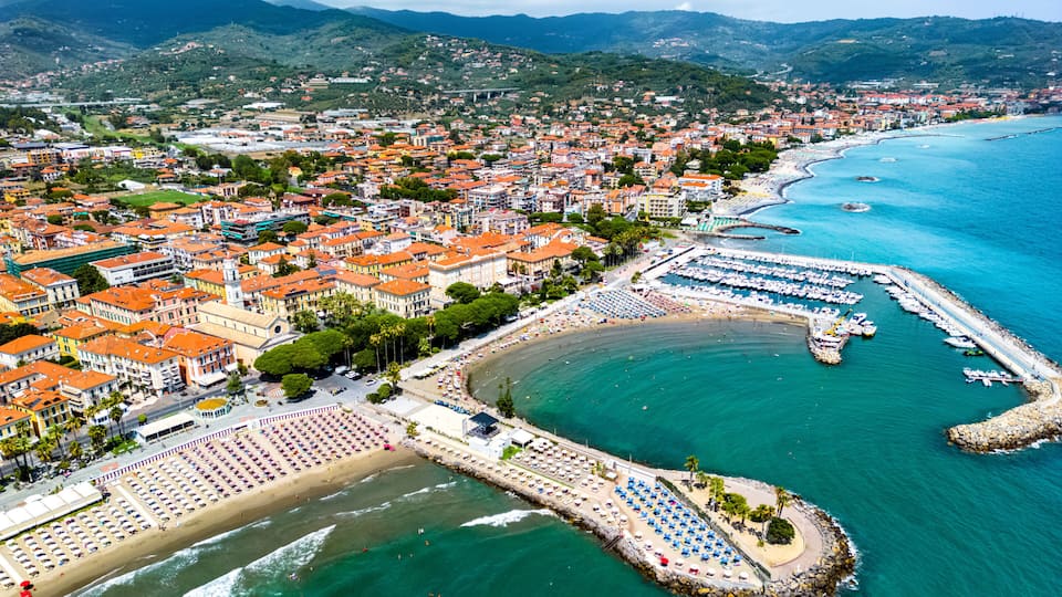 A coastal city with a marina, beach, and mountainous backdrop.