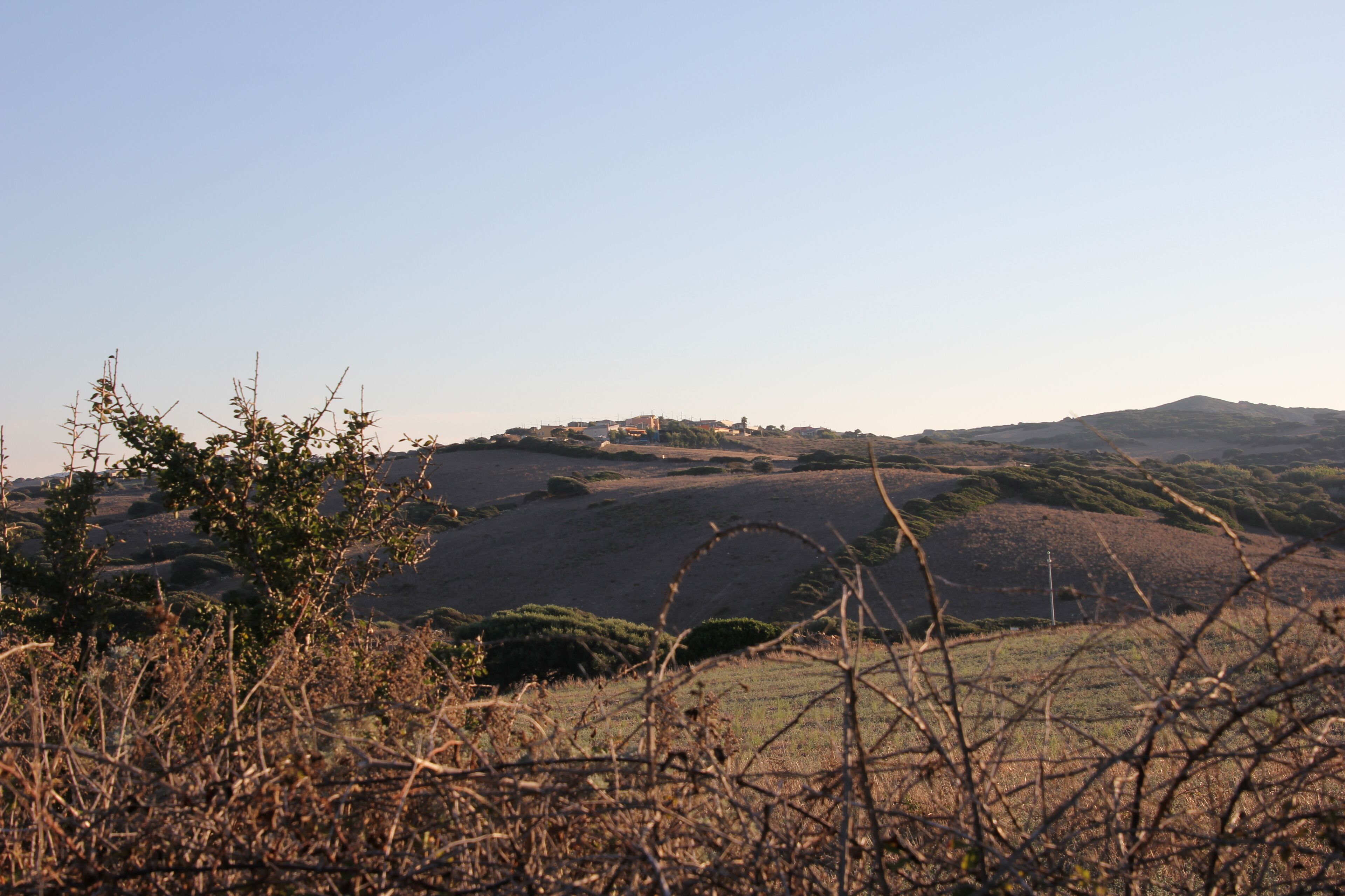 Rolling hills, a distant building, and sparse vegetation.