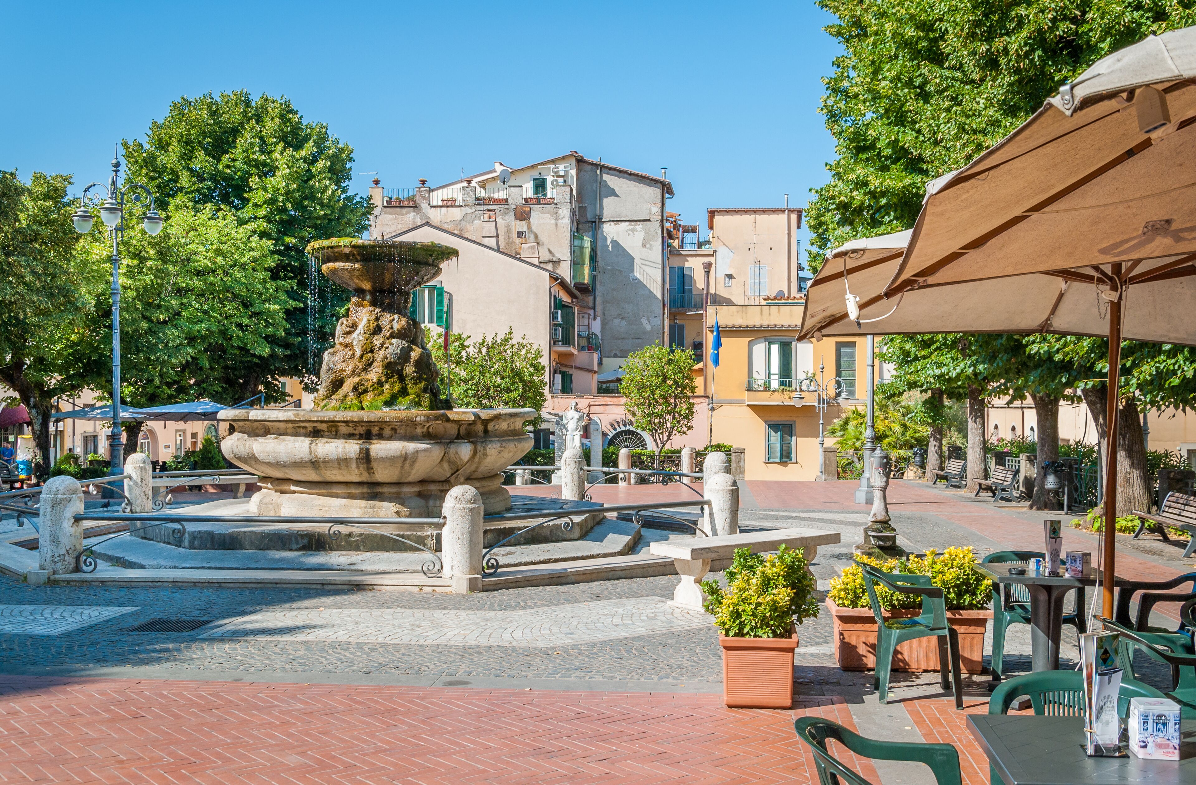 A fountain in a square surrounded by buildings and trees.