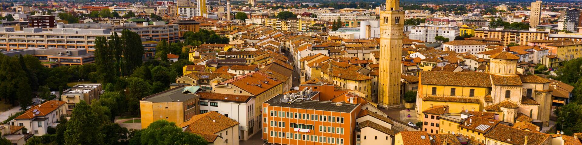A cityscape with a prominent church tower, surrounded by historic buildings and a mountainous backdrop.