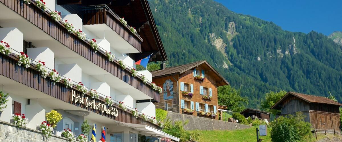 A mountain town with a hotel named "Hotel Gasthof Oberland" and a car parked in front.