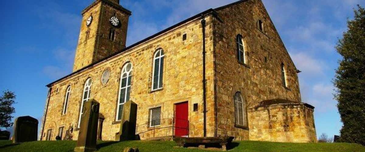 A stone church with a clock tower and a red door.