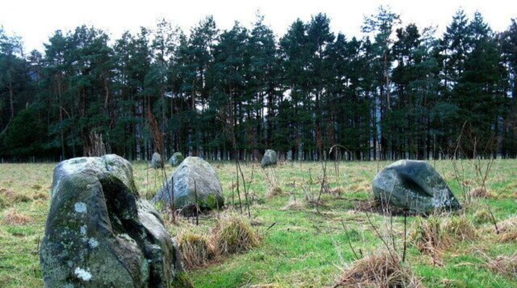 Fortingall Stone Circles To the E of Fortingall stand three groups of standing stones. Closest to the road are a group of four stones and a group of three stones , while further into the field, closer to the river, is another group of three. Originally they had been four-poster variants, each comprising of four large stones at the corners of a rectangle, with four smaller stones mid-way between the larger ones. In both cases, the missing five stones had been pushed over and buried deeply in prepared pits at some point in the nineteenth century. The date is known as one of the stones was found to have a Victorian beer bottle under it.