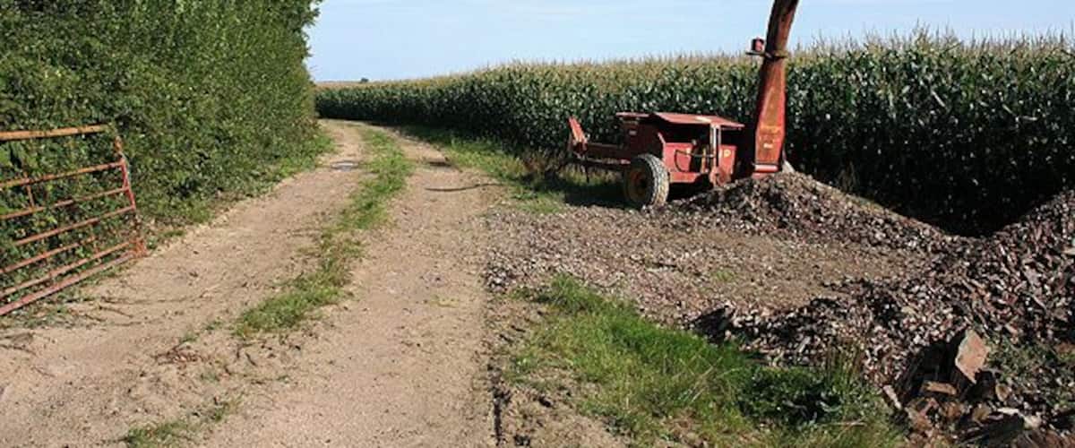 A dirt path with a tractor in a field.