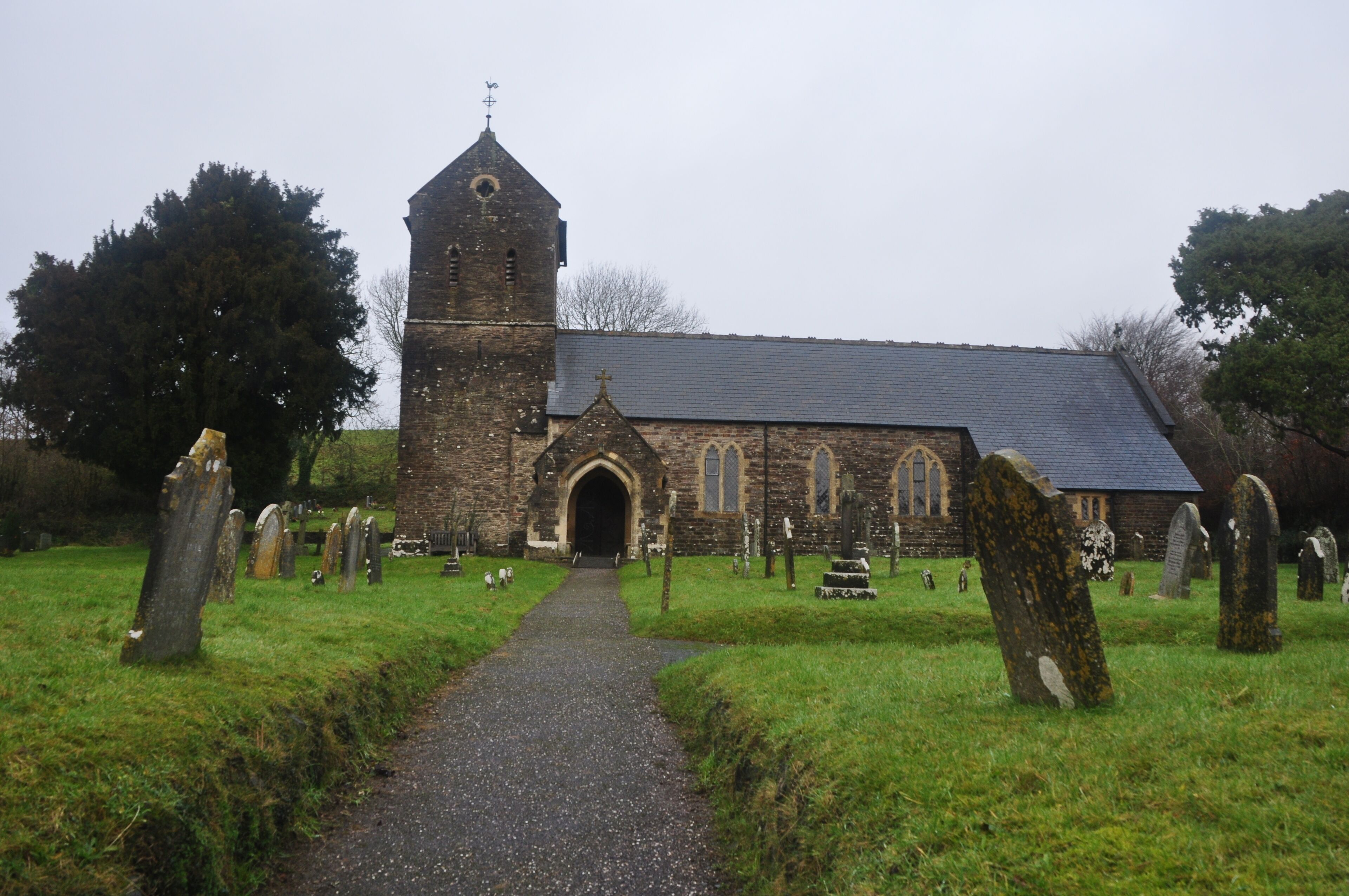 A church with a tall tower and a graveyard with headstones.