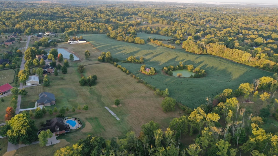A rural landscape with fields, a pond, and scattered houses.