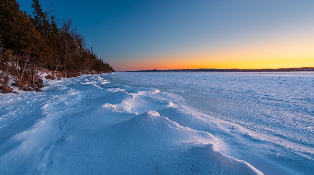 Snow drifts along frozen shoreline of Torch Lake in Northern Michigan.